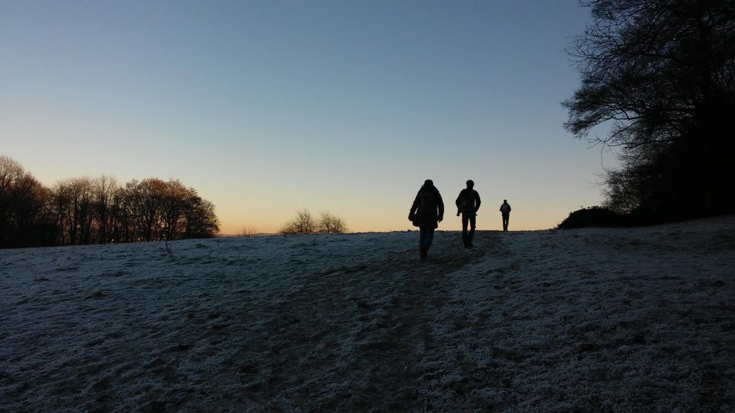 Twee wandelaars op een heuvel bij zonsondergang