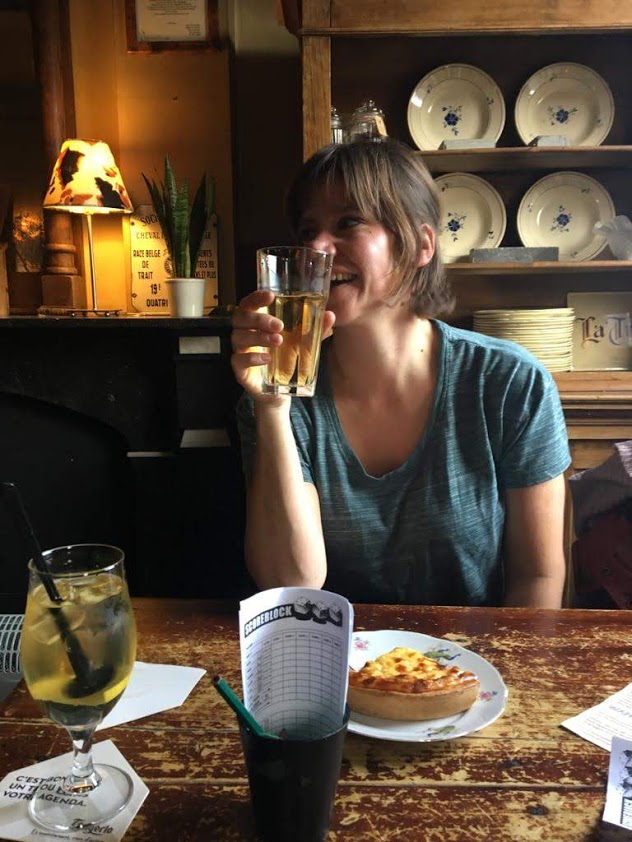 Cecile met een glas aan tafel in een gezellig café