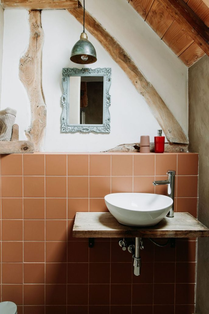 Badkamer met roze tegels en een houten wastafel