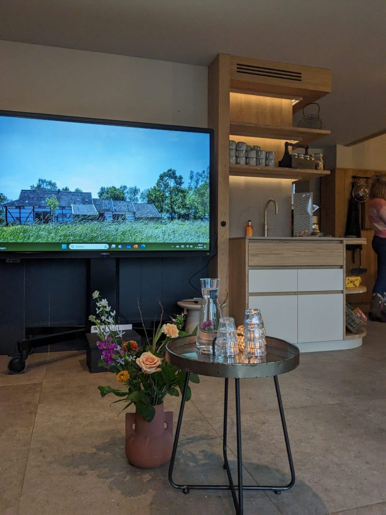 Vergaderruimte met groot scherm en een boeket bloemen