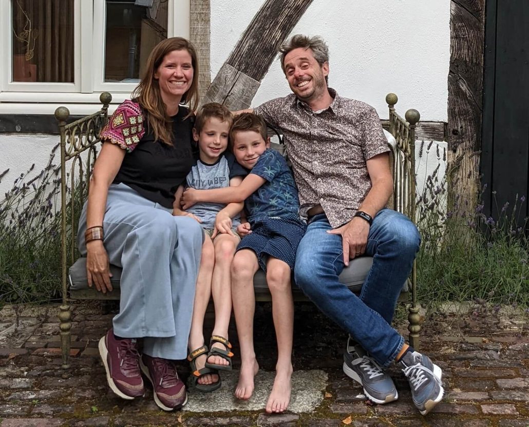 Bart, Cecile en hun twee zoons op een bankje voor het vakwerkhuis