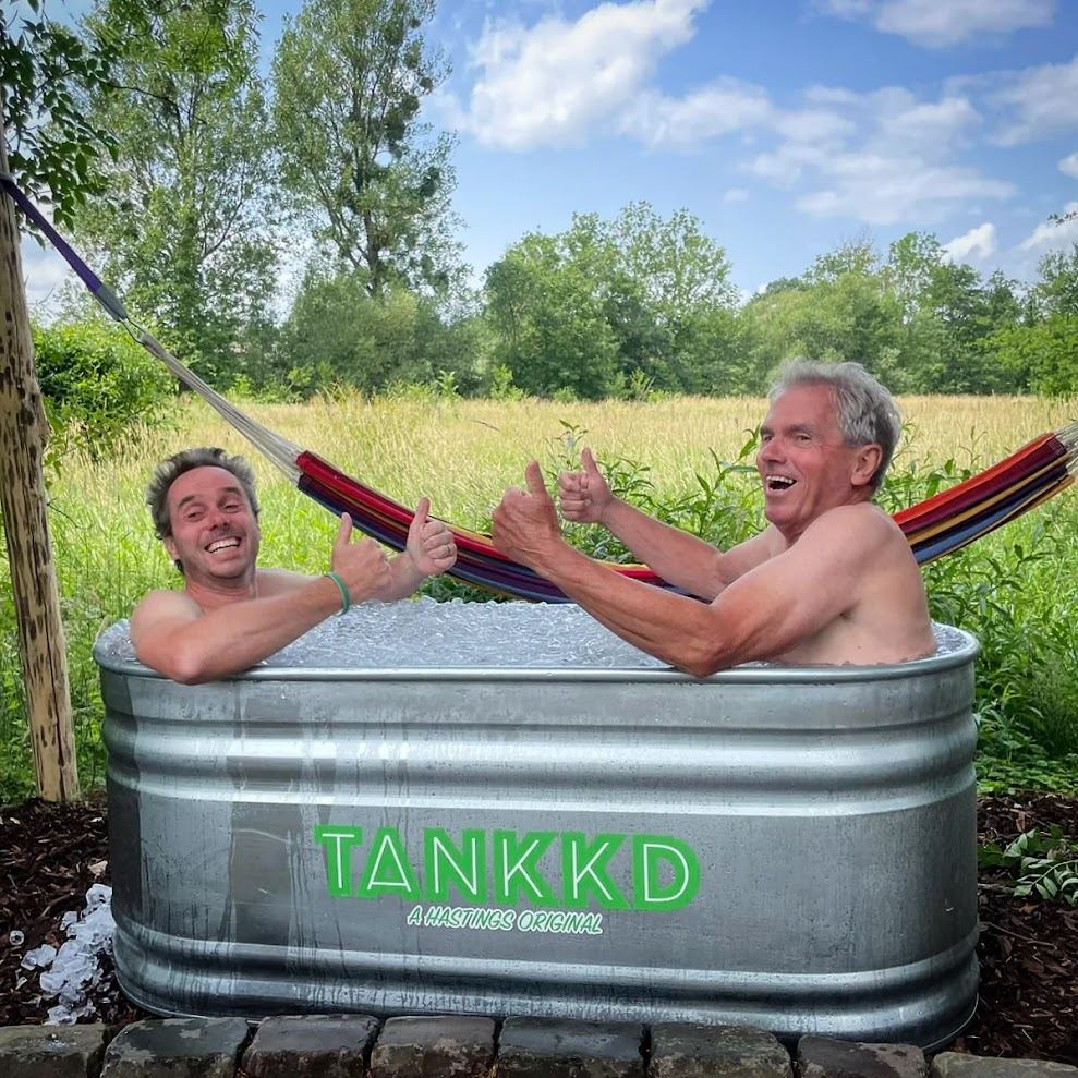 Twee mannen in een ijsbad in de wei, met een hangmat erachter